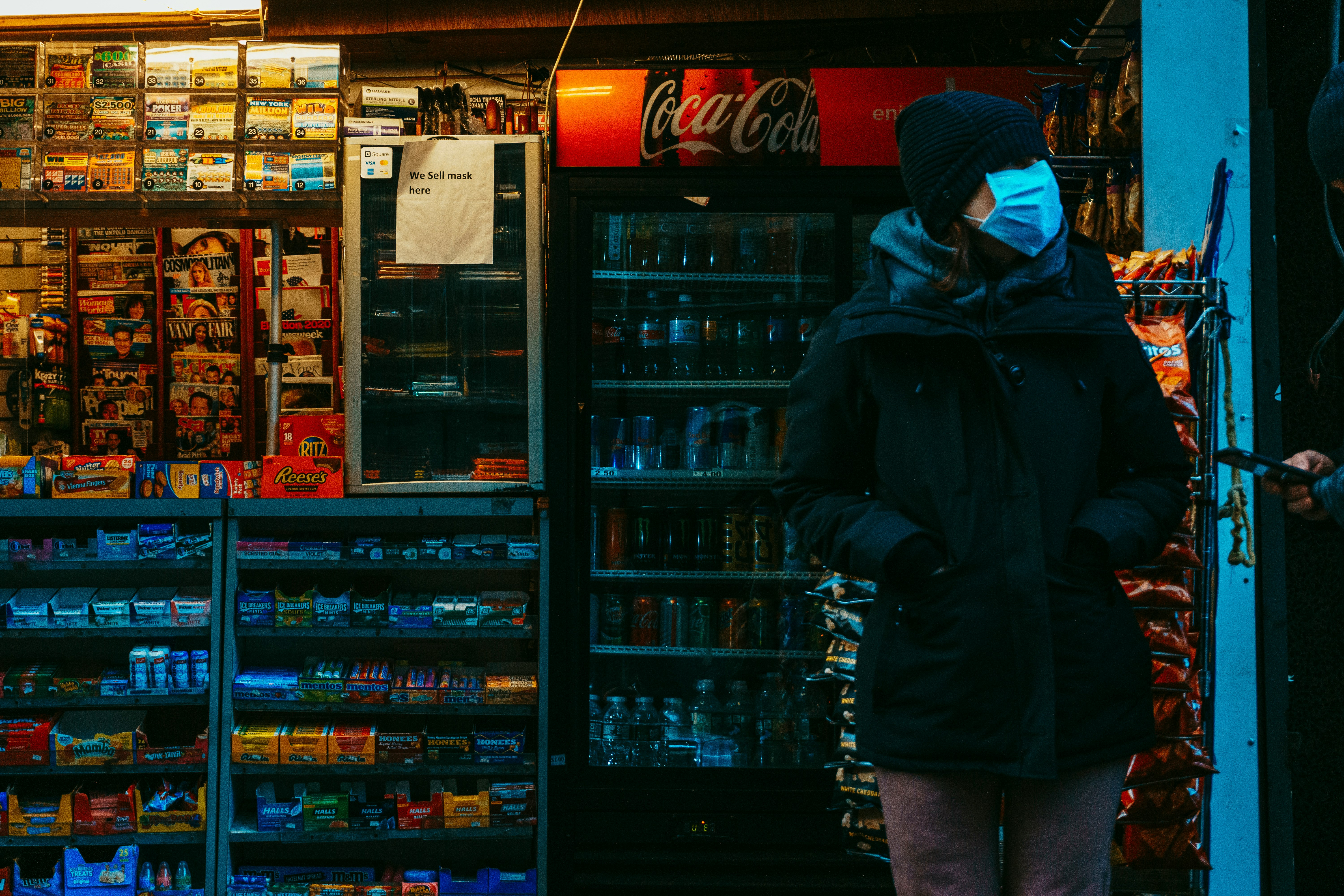 man in black jacket standing near coca cola vending machine